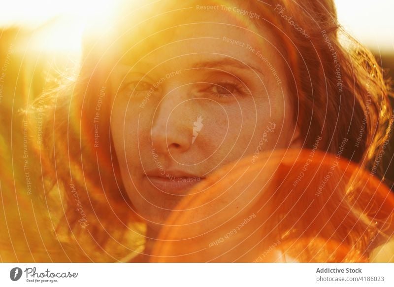 Verträumte Frau schaut in die Kamera gegen den Sonnenuntergangshimmel sich[Akk] entspannen Natur Sonnenlicht ruhig nachdenken nachdenklich Anmut Windstille
