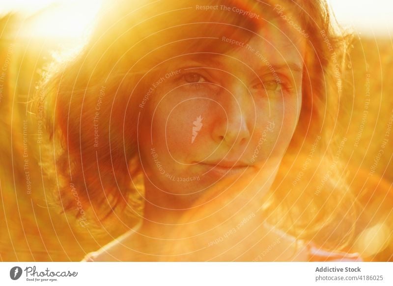 Verträumte Frau schaut in die Kamera gegen den Sonnenuntergangshimmel sich[Akk] entspannen Natur Sonnenlicht ruhig nachdenken nachdenklich Anmut Windstille