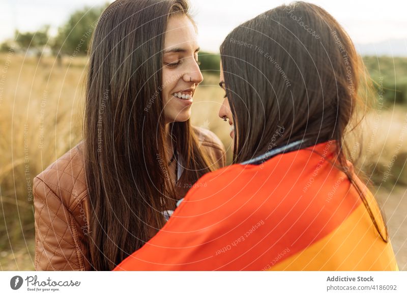 Lesbisches Paar mit Regenbogenfahne umarmt sich in der Natur lesbisch Frauen Umarmung Fahne umhüllen Liebe lgbt Freundin sanft gleich Partnerschaft