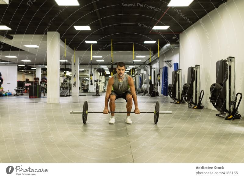 Konzentrierter junger Sportler beim Training mit Gewichten im Fitnessstudio Gewichtheben Curl-Hantel stark Wohlbefinden anstrengen Ausdauer Übung Mann physisch