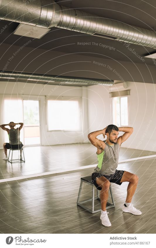 Junger sportlicher Mann macht Kniebeugen auf einer Stufenplattform im Studio Kniebeuge mit einem Bein Training Übung Energie Ausdauer physisch Sport
