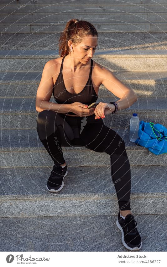 Sportliche Frau mit Smartphone und Fitness-Tracker Training benutzend prüfen Telefon Mobile ruhen passen digital Apparatur Gerät Wellness Gesundheit