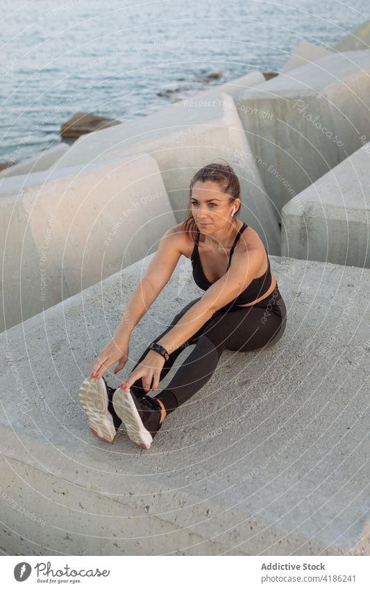 Sportlerin bei Dehnungsübungen auf dem Wellenbrecher Training Übung Bein Stauanlage Fitness aktiv Aufwärmen passen Frau Wellness Gesundheit Wohlbefinden Läufer
