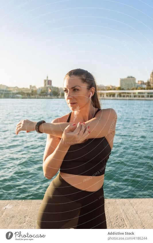 Sportliche Frau beim Training an der Uferböschung Übung Dehnung Stauanlage Fitness Aufwärmen passen Hafengebiet Wellness Gesundheit Wohlbefinden Athlet