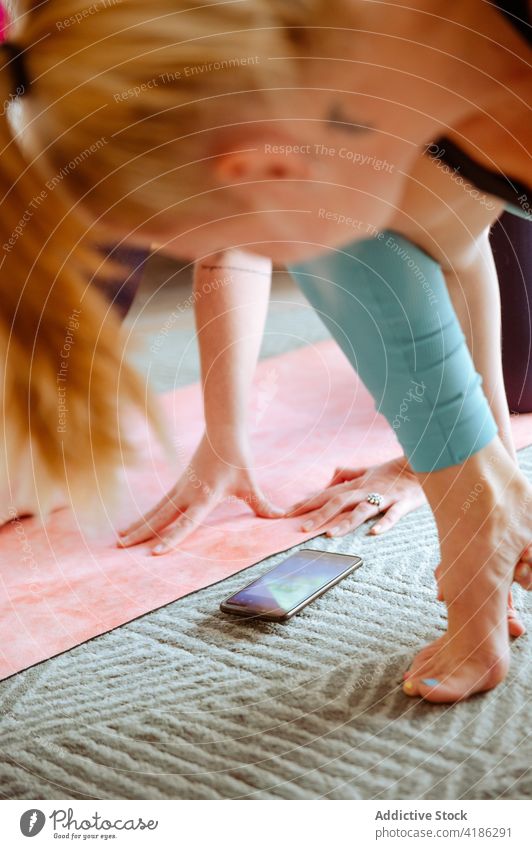 Flexible Frau macht Yoga in Crooked Monkey on Forearm Pose mit Handy Asana üben beweglich Dehnung Zen schlank Gesundheit Wellness Gleichgewicht Wohlbefinden
