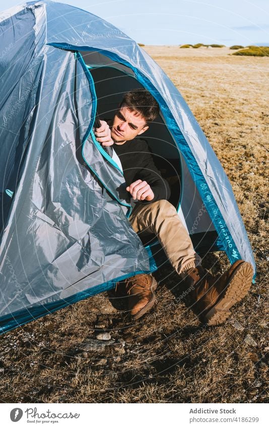 Seriöser junger Mann, der sich während eines Wanderausflugs im Zeltlager entspannt ruhen Lager Trekking Reisender trendy ernst Natur Fernweh Wanderung männlich