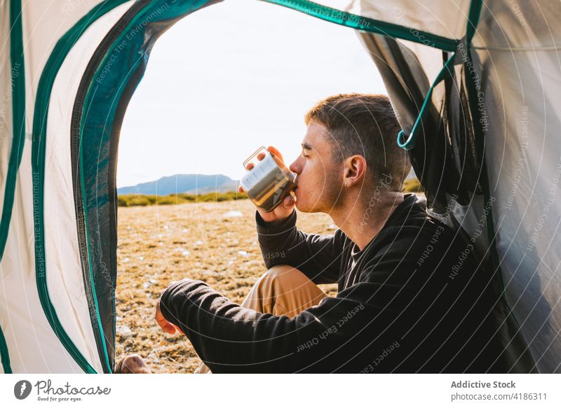 Stilvoller junger Mann genießt ein heißes Getränk beim Camping in den Bergen trinken Zelt Lager Erholung Wanderer Heißgetränk selbstbewusst Natur