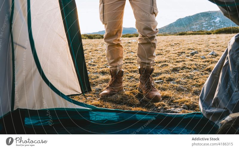Anonymer Wanderer, der an einem sonnigen Tag in der Nähe seines Zeltes auf dem Campingplatz steht Person Lager Reisender Ausflug Natur Hochland Wanderung