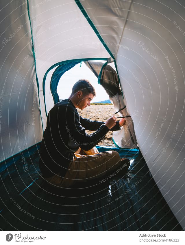 Junger stilvoller Mann sitzt im Zelt beim Camping Lager Wohnmobil Konzentration ruhen Wanderung Ausflug allein Natur Aktivität Hobby männlich jung lässig Reise