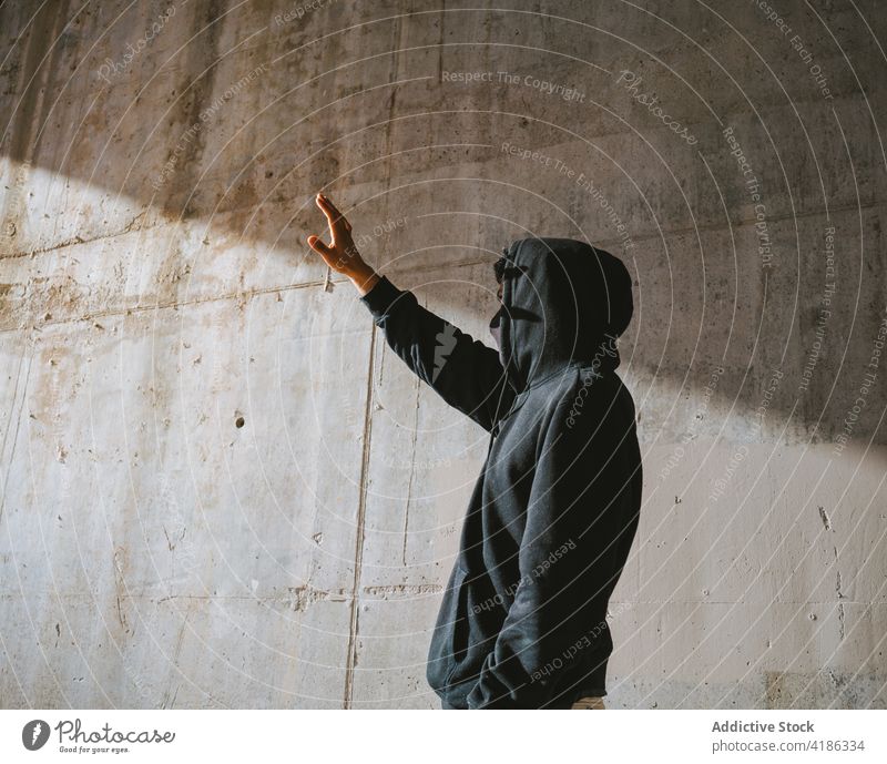 Anonymer Mann, der auf der Straße steht und die Augen vor Sonnenlicht schützt Deckblatt allein neue Normale Stil Großstadt cool Schatten einsam Beton Wand