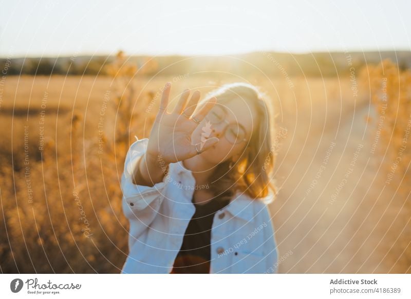 Stilvolle junge Frau zeigt Hand in der Landschaft im Sonnenlicht Feld fünf Natur sich[Akk] bewegen selbstbewusst aktiv Feiertag Pflanze trendy trocknen Gras