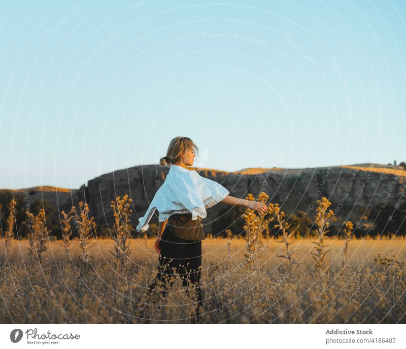 Trendige junge Frau, die im Urlaub auf dem Land in einem Feld am Hang spazieren geht Spaziergang Landschaft Sonnenuntergang sich[Akk] entspannen ländlich Hügel
