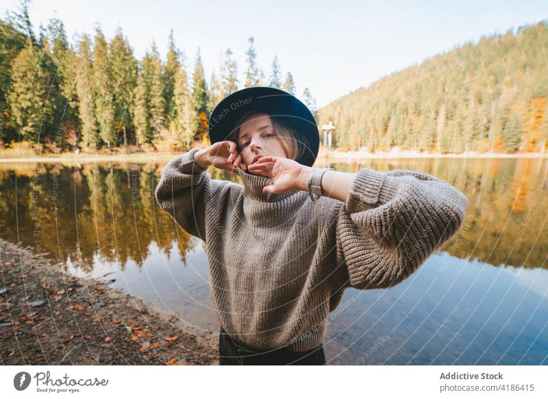 Stilvoller Reisender mit Hut am Ufer eines Sees Tourist cool Ausflug Reflexion & Spiegelung Baum Frau Himmel stylisch Bekleidung Kleidungsstück selbstbewusst