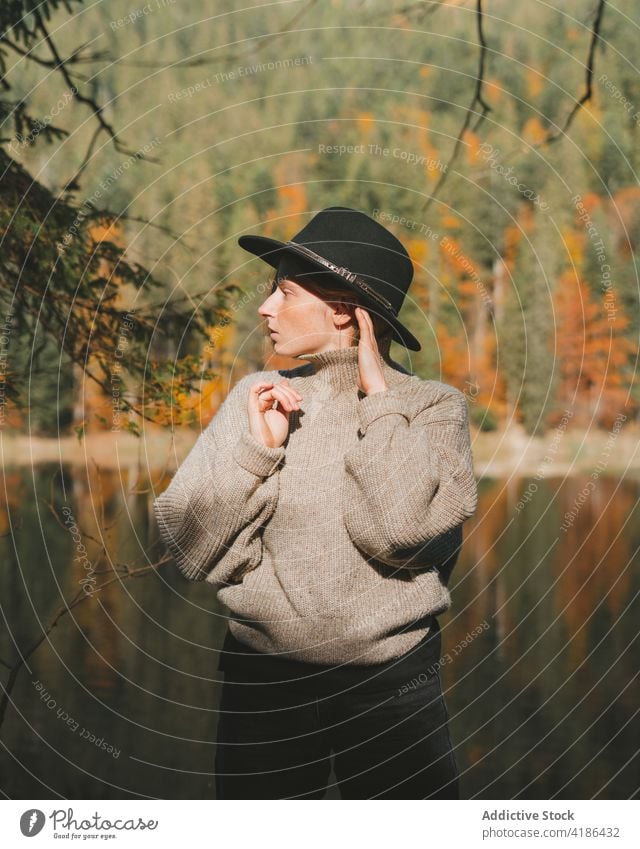 Stilvoller Reisender mit Hut am Ufer eines Sees Tourist cool Ausflug Reflexion & Spiegelung Baum Frau Himmel stylisch Bekleidung Kleidungsstück selbstbewusst