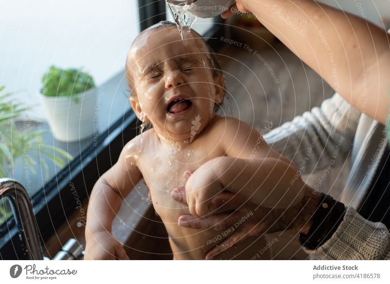 Crop Eltern baden Baby in der Küche Waschbecken Bad Wasser Hygiene Mutter Vater Kleinkind Sauberkeit eingießen niedlich Zusammensein Kind Familie Mama heimwärts