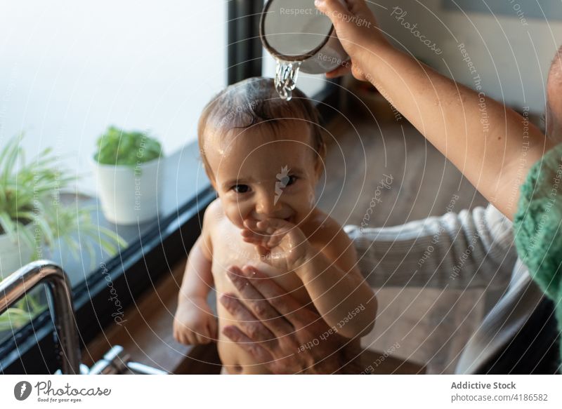 Eltern baden Baby im Waschbecken Waschen Bad Wasser Hygiene Mutter Vater Lächeln Kleinkind Küche Sauberkeit eingießen niedlich Freude Inhalt Zusammensein Kind