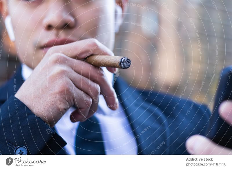 Geschäftsmann raucht Zigarre in einem Straßencafé Rauch Café Unternehmer Browsen Smartphone reich Vermögen benutzend männlich asiatisch ethnisch Mann Tisch