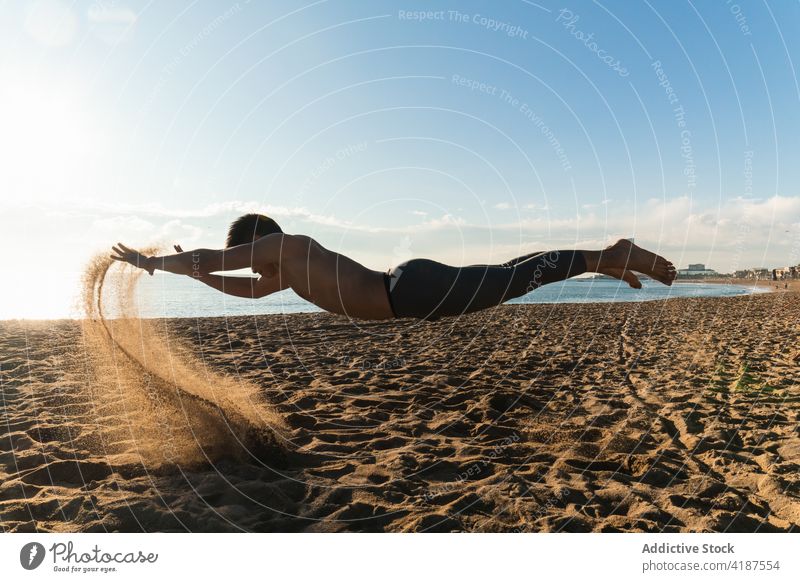 Sportlicher Mann, der während des Trainings über dem Sand schwebt Sportler schweben Strand springen sportlich aktiv Übung Fliege Aktivität Lifestyle Energie