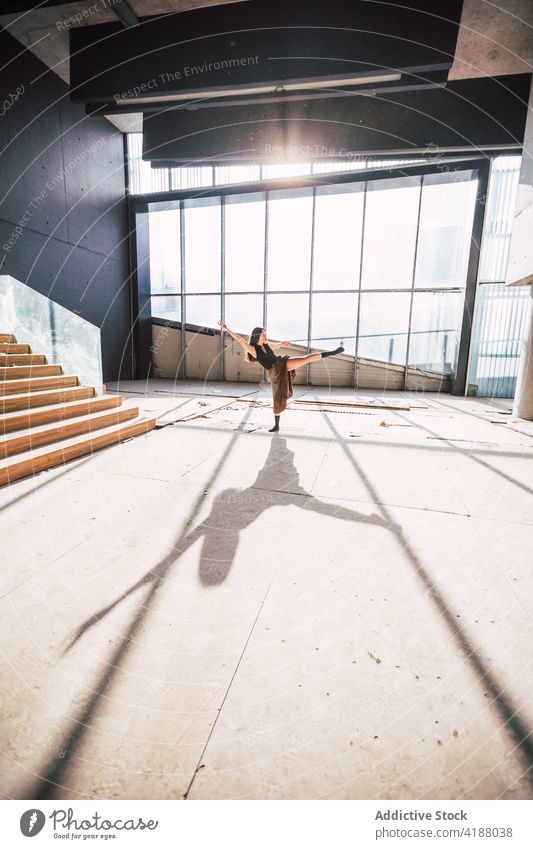 Anonymer Tänzer, der während einer Probe im Gebäude tanzt Künstler Tanzen Choreographie Bein angehoben Arm angehoben ausführen Schatten Theater Frau vorbereiten