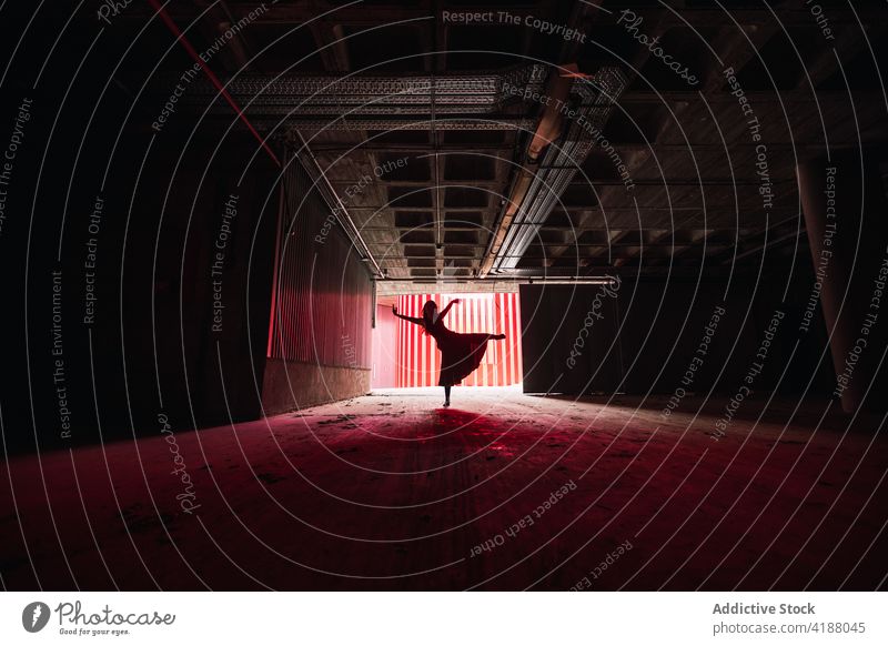 Unerkennbare Künstlersilhouette bei einem Auftritt in einem dunklen Auditorium Tänzer Tanzen Leistung Probe professionell Arme hochgezogen Bein angehoben
