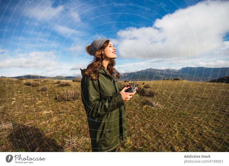 Reisender mit Drohnencontroller auf Wiese unter blauem Wolkenhimmel abgelegen Regler uav schmollende Lippen genießen Kontrolle Frau benutzend Ausflug Gerät