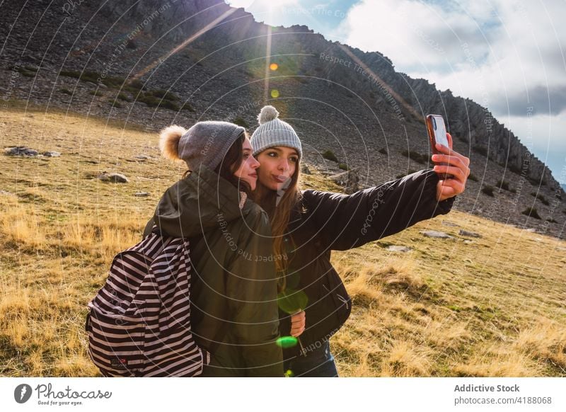 Weibliche Wanderer nehmen Selfie mit Handy in den Bergen an einem sonnigen Tag Frauen Trekker teilen Smartphone Lachen interagieren Urlaub Selbstporträt