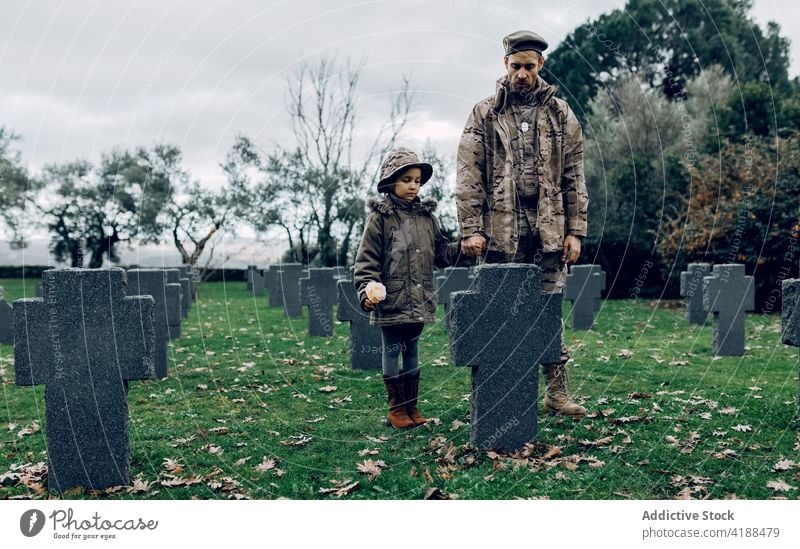 Mann mit kleinem Mädchen steht am Grab eines Soldaten Militär Friedhof Held Gedächtnis Trauer Bestattung Grabstein männlich Denkmal verärgert Grabmal Tod stumm