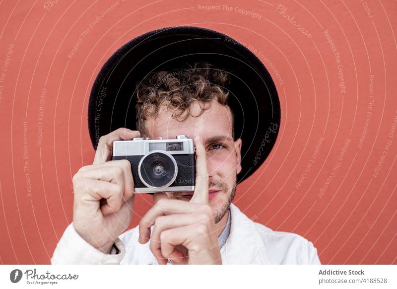Zufriedener junger Mann, der mit einer alten Kamera auf der Straße fotografiert fotografieren retro Fotoapparat selbstbewusst Stil Persönlichkeit Porträt