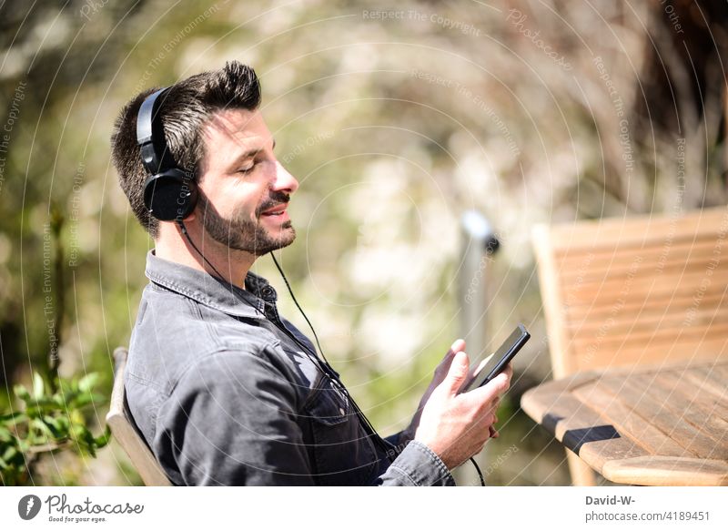 Mann streamt über sein Handy Musik und singt mit streaming Kopfhörer singen Gute Laune happy Musik hören Fröhlichkeit lässig Zufriedenheit