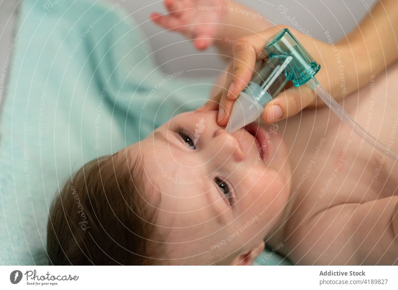 Crop-Mutter saugt den Nasenschleim des süßen Babys mit einem Sauger ab saugen Aspirator Schleim nasal Kinderbetreuung Sog Säugling Pflege Mutterschaft Kindheit