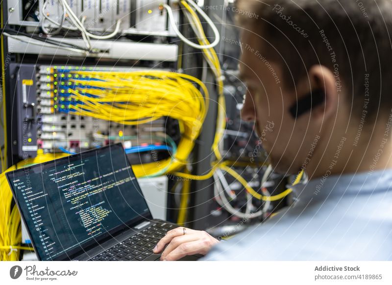 Männlicher Ingenieur, der das System im Rechenzentrum kontrolliert Mann Assistent setzen Kabel benutzend Laptop Netzwerk Anschluss prüfen männlich
