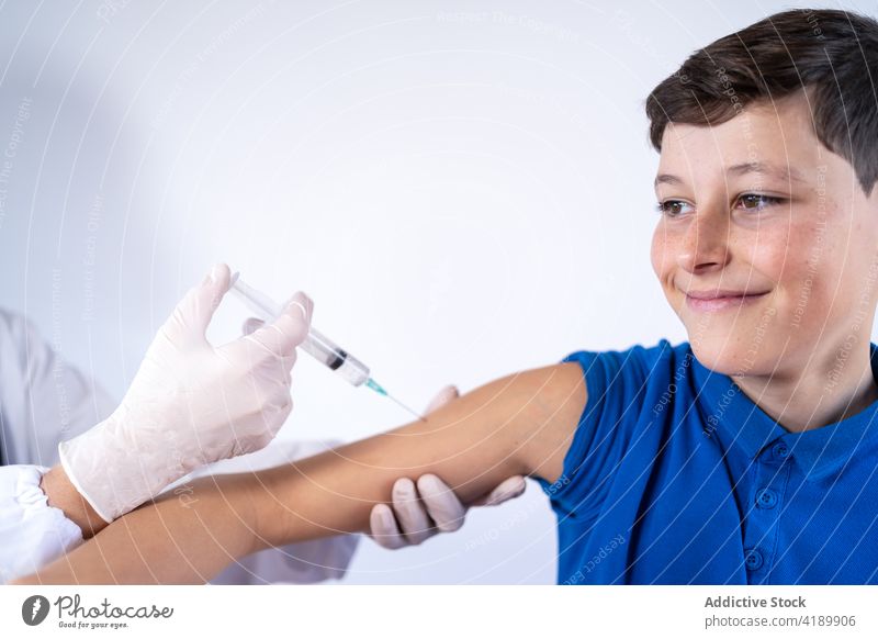 Arzt macht Injektion für glücklichen Jungen Kind Einspritzung Impfstoff Coronavirus Spritze Glück Schmerz Lächeln wehtun Bund 19 COVID19 Pandemie Leckerbissen