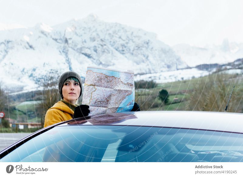 Frau prüft Standort auf Karte in der Nähe des Autos im verschneiten Hochland Autoreise Landkarte navigieren Berge u. Gebirge PKW reisen Winter Anleitung