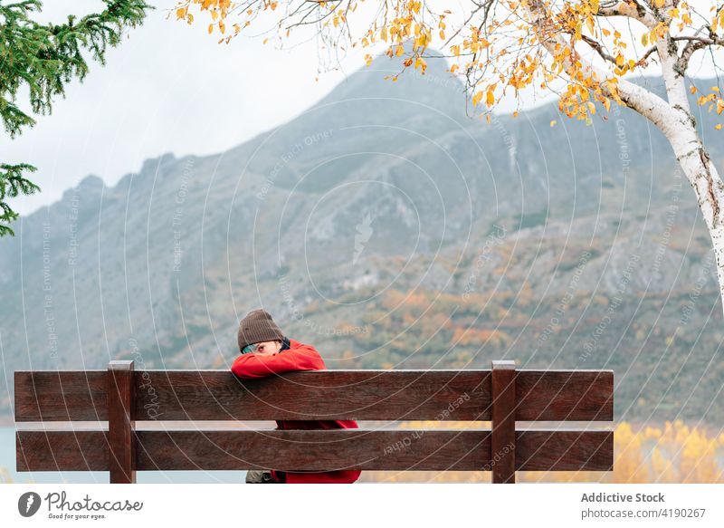 Frau sitzt auf einer Bank in einem majestätischen Herbstpark bewundern Park Berge u. Gebirge Seeufer ruhen genießen malerisch schwer friedlich Kamm fallen