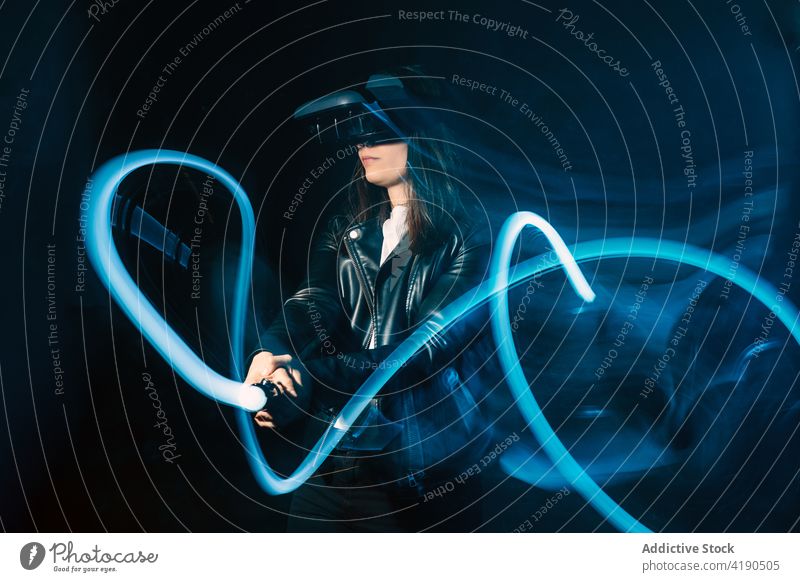 Anonyme Frau in VR-Headset mit Controller Schutzbrille Bewegung Game-Controller neonfarbig Licht Virtuelle Realität Einfluss blau Technik & Technologie