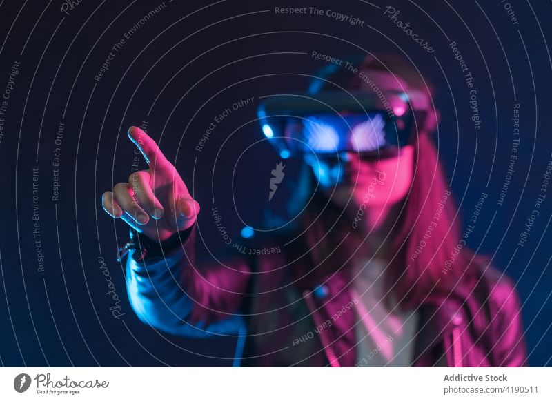 Anonyme Frau mit VR-Brille im Neonlicht Schutzbrille Headset neonfarbig Licht ausdehnen Virtuelle Realität Technik & Technologie Cyberspace leuchten simulieren