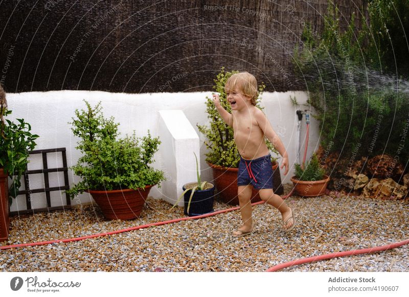 Konzentriertes Kind beim Bewässern des Rasens im Hinterhof Wasser Spaziergang Fokus Schlauch Feiertag Kindheit spielen idyllisch Urlaub Glück Sommer Landschaft