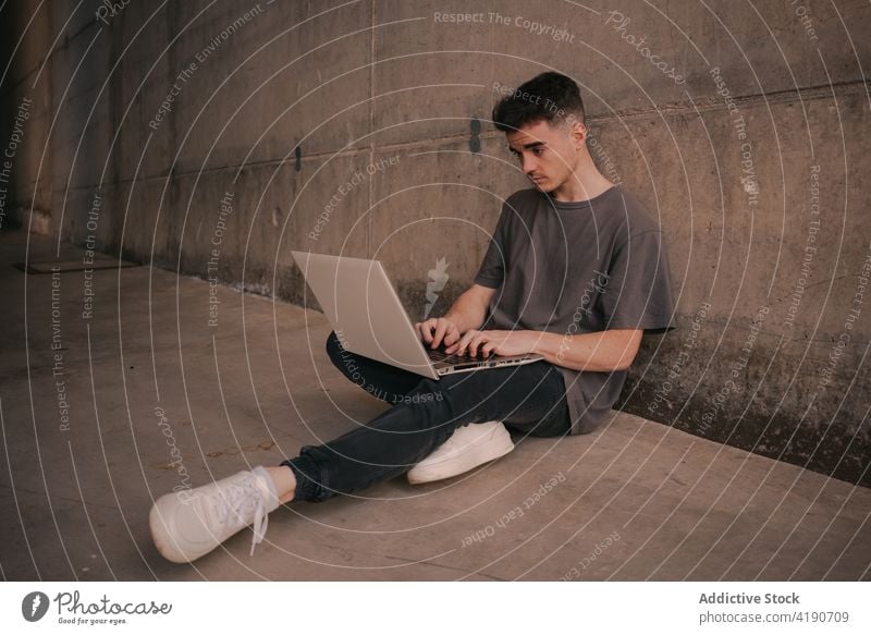 Konzentrierter junger männlicher Freiberufler, der mit Abstand am Laptop arbeitet Mann Arbeit freiberuflich Internet ernst soziale Netzwerke Konzentration Job
