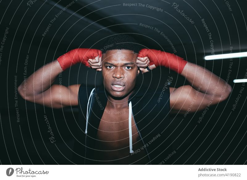 Kräftiger schwarzer Boxer schaut beim Training in die Kamera Sport Übung üben stark Kraft Mann Porträt maskulin Gebäude Hand umhüllen Klebeband muskulös