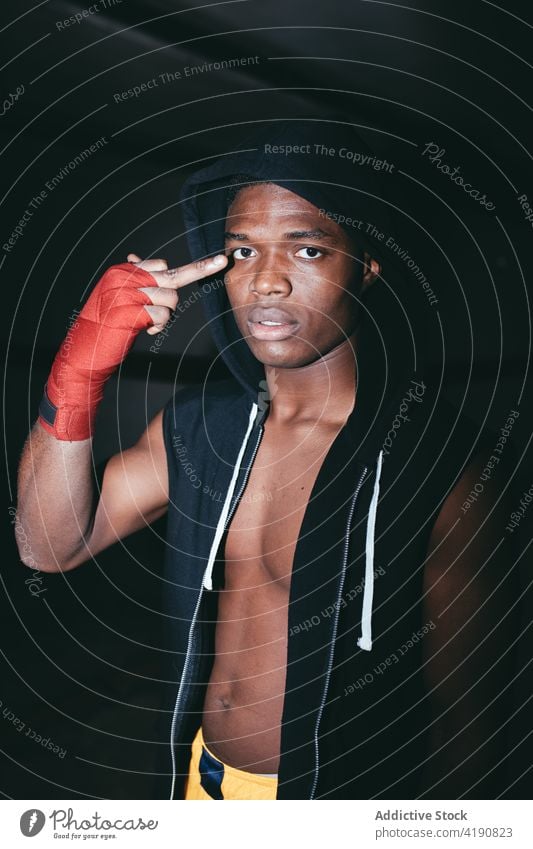 Ethnischer Boxer mit Bizeps, der eine Fick-Geste zeigt Sportler ficken unverschämt angriffslustig auflehnen vulgär Mittelfinger anstößig Porträt Mann Unterleib