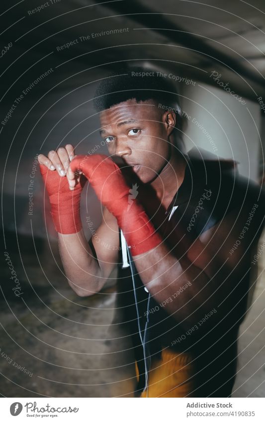 Kräftiger schwarzer Boxer mit Kopfhörern beim Training Sport Übung üben stark Kraft Mann Porträt maskulin Gebäude Hand umhüllen Klebeband muskulös
