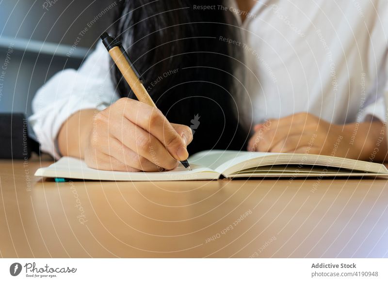 Frau schreibt Notizen in Notizblock während Fernarbeit Arbeit schreiben Notebook Job Schreibstift Beruf Arbeitsplatz beschäftigt lernen zur Kenntnis nehmen