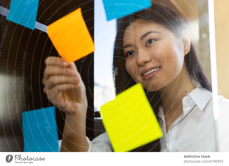 Inhalt Asiatische Geschäftsfrau klebt Papieraufkleber auf Glaswand Unternehmer setzen Aufkleber Plan Management analysieren Projekt Frau Büro Material