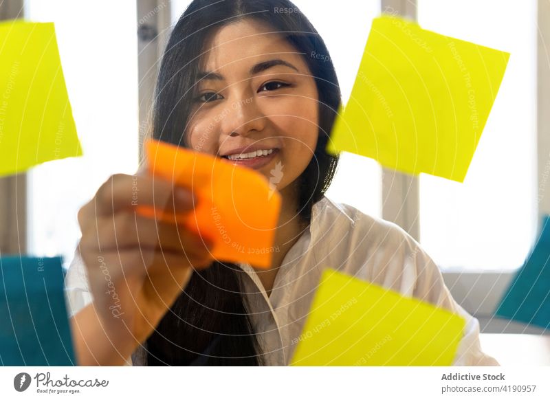 Inhalt Asiatische Geschäftsfrau klebt Papieraufkleber auf Glaswand Unternehmer setzen Aufkleber Plan Management analysieren Projekt Frau Büro Material
