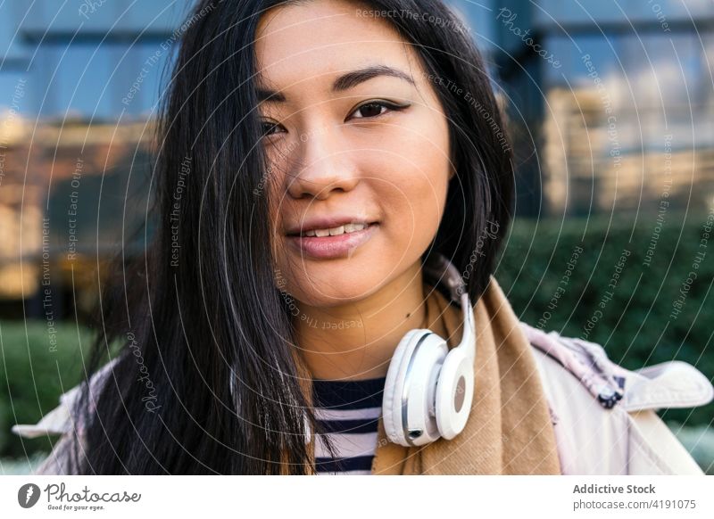 Asiatische Frau auf der Straße stehend froh Individualität vertikal Wald Gebäude Persönlichkeit Optimist sorgenfrei Mantel Lächeln positiv Pflanze angenehm