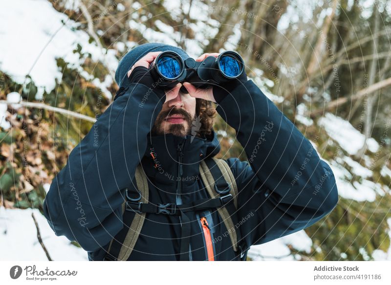 Reisender Mann schaut in Fernglas im Winterwald reisen Wald Abenteuer Wanderer erkunden warme Kleidung männlich Saison Schnee Natur Wälder Urlaub Tourismus kalt
