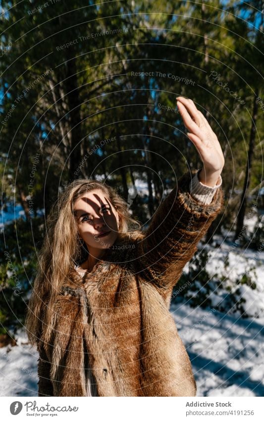 Frau bedeckt Gesicht vor der Sonne im verschneiten Wald Winter Deckblatt sonnig Sonnenlicht Winterzeit schlendern Schatten Wälder Fell Mantel warm