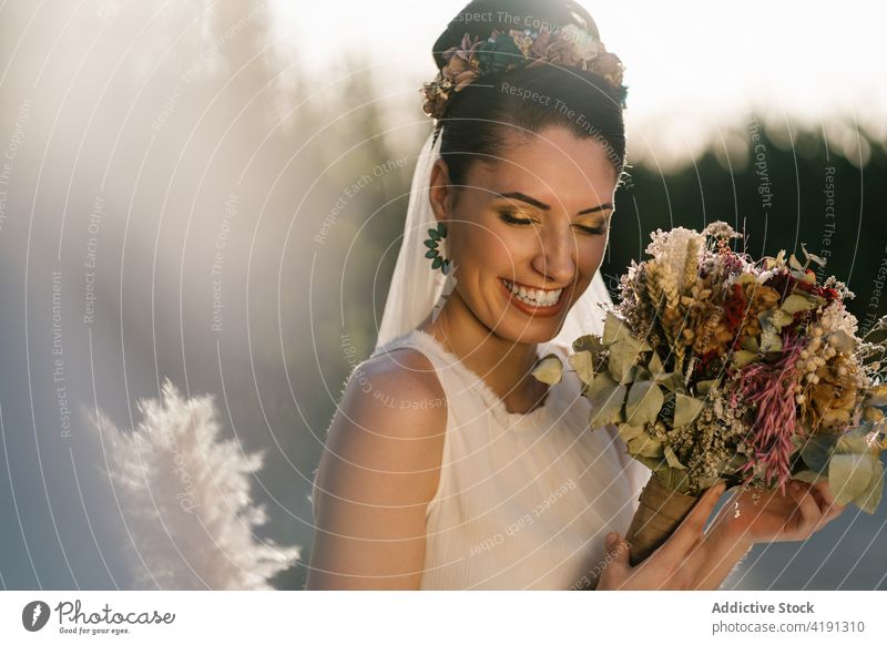 Fröhliche Braut mit Blumenstrauß im Garten hochzeitlich heiter charmant Hochzeit weißes Kleid Jungvermählter Frau Sommer ausgefallen Veranstaltung elegant