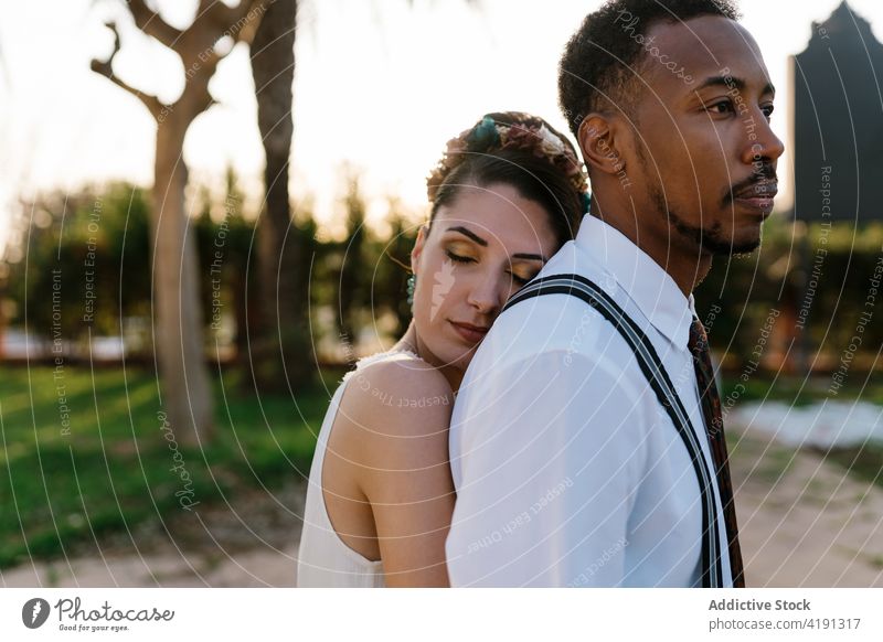 Fröhliches frisch verheiratetes Paar, das sich im Garten umarmt Jungvermählter Umarmung Braut striegeln Hochzeit Liebe Zusammensein multiethnisch