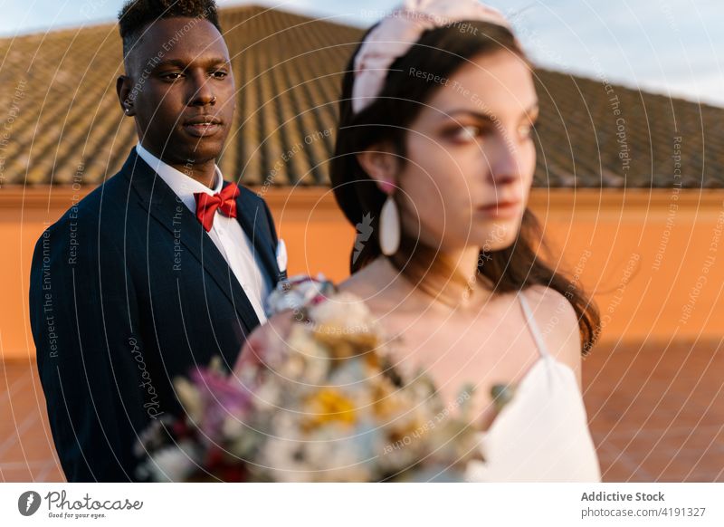 Multiethnisches frisch vermähltes Paar auf der Terrasse Jungvermählter Angebot Hochzeit Blumenstrauß Braut striegeln Zusammensein schwarz Afroamerikaner